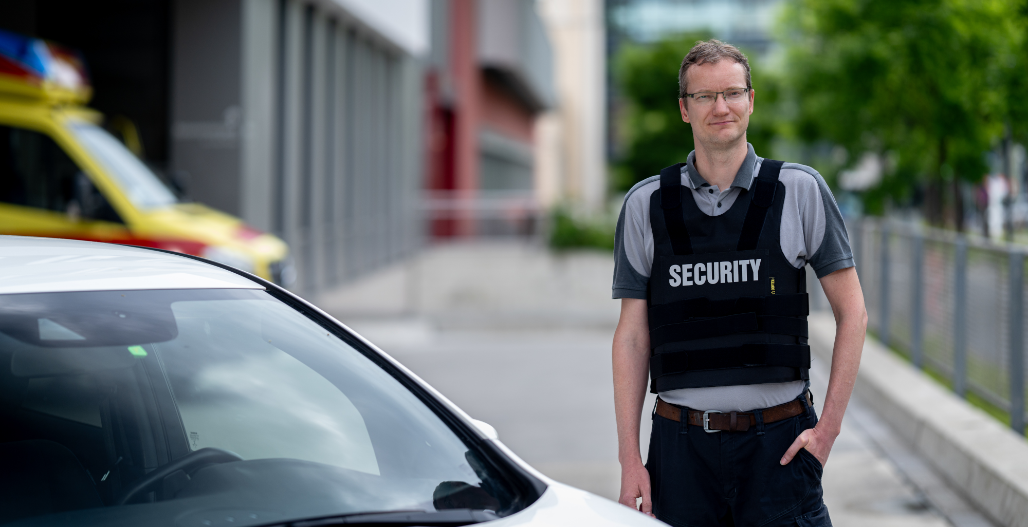 Eine Person mit "Security" Weste vor einem Fahrzeug